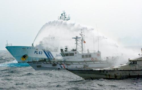 臺灣“海巡署”的巡邏船（中）在掩護保釣船“全家?！碧枺ㄓ遥┒惚苋毡竞Ｉ媳０矎d巡視船的水炮攻擊。