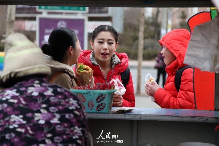 2014年2月17日，山東濱州，背著大包小包的藝考考生在濱州學(xué)院考點外買飯。