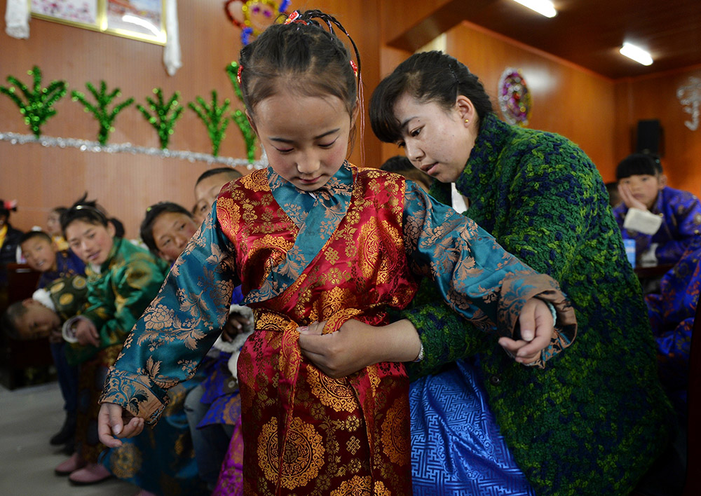 2月27日，在西藏自治區(qū)兒童福利院，來自拉薩市尼木縣的“愛心媽媽”德慶旺姆（右）在為來自那曲地區(qū)的嘎瑪曲宗換上節(jié)日盛裝。